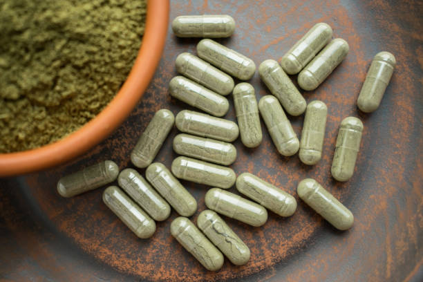 suplemento verde de kratom cápsulas y polvo en la placa marrón - morfina medicamento fotos fotografías e imágenes de stock