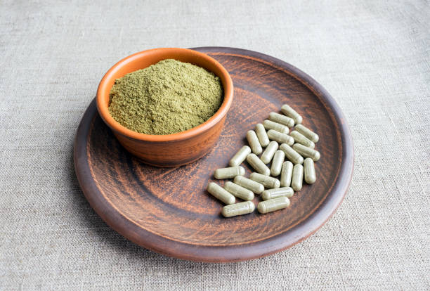 Supplement kratom green capsules and powder on brown plate Supplement kratom green capsules and powder on brown plate. Herbal product alt-medicine kratom is  opioid. Home alternative pain remedy, opioid addiction, dangerous painkiller, overdose. Close up morphine drug stock pictures, royalty-free photos & images