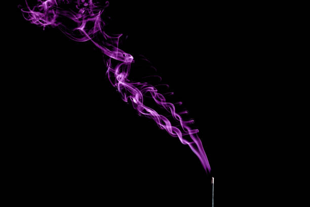 Incense aroma stick with purple smoke on black background