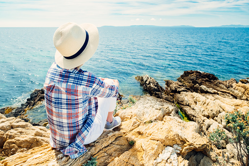 Senior woman relaxing on the rocky seashore of the Provence coast of France.