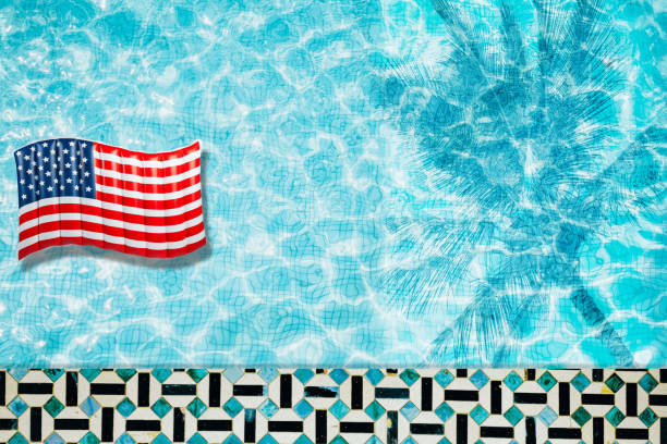 istock Pool floats, rings floating in a refreshing blue swimming pool with palm tree leaf shadows in water 975662534