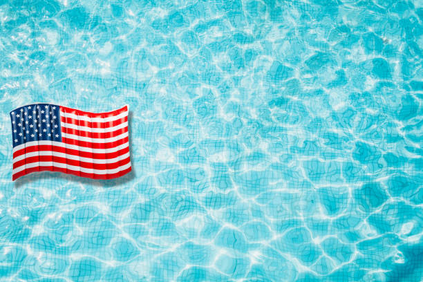 istock Pool floats, rings floating in a refreshing blue swimming pool with palm tree leaf shadows in water 975662584