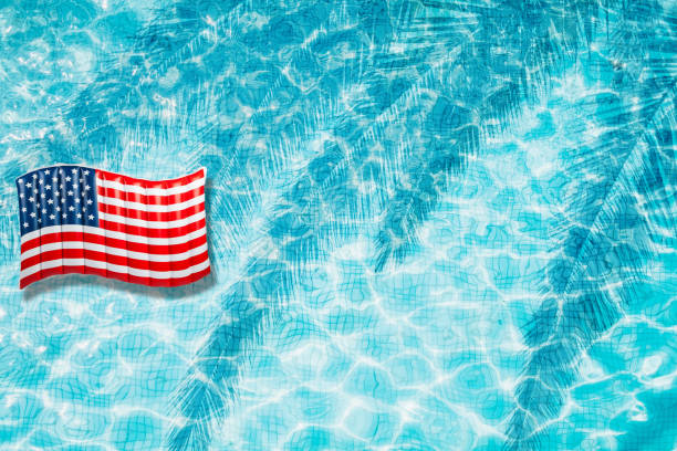 istock Pool floats, rings floating in a refreshing blue swimming pool with palm tree leaf shadows in water 975662614