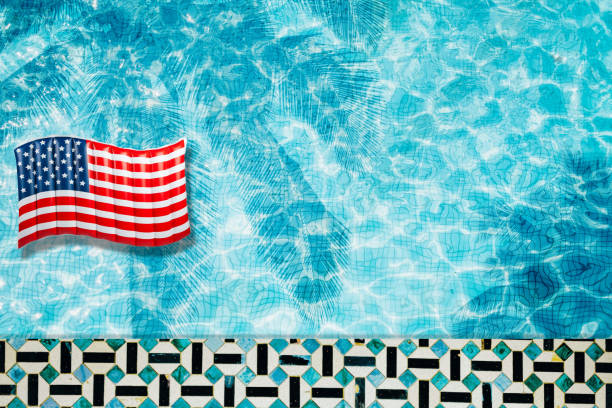 istock Pool floats, rings floating in a refreshing blue swimming pool with palm tree leaf shadows in water 975662652
