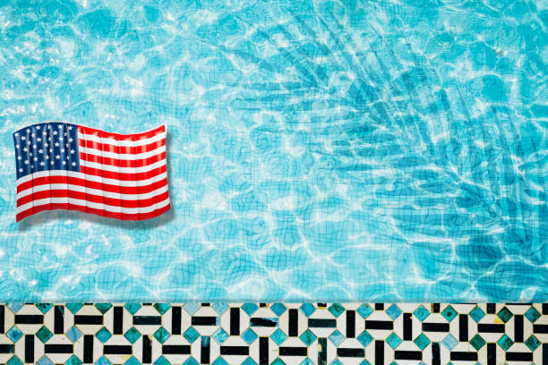 istock Pool floats, rings floating in a refreshing blue swimming pool with palm tree leaf shadows in water 975662724