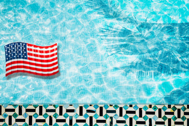istock Pool floats, rings floating in a refreshing blue swimming pool with palm tree leaf shadows in water 975662768