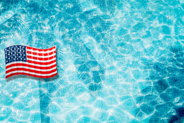 istock Pool floats, rings floating in a refreshing blue swimming pool with palm tree leaf shadows in water 975662772