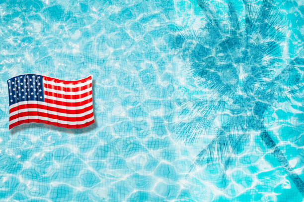istock Pool floats, rings floating in a refreshing blue swimming pool with palm tree leaf shadows in water 975662778