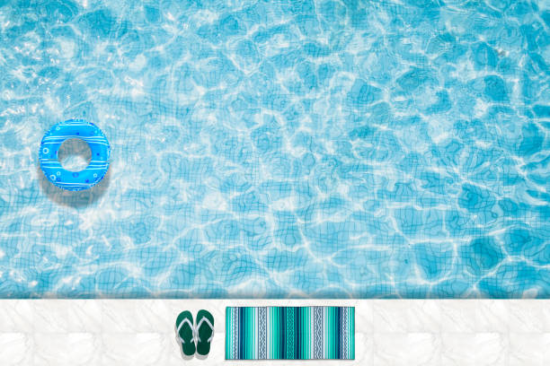 istock Pool floats, rings floating in a refreshing blue swimming pool with palm tree leaf shadows in water 975665742