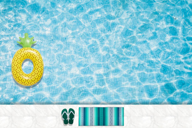 istock Pool floats, rings floating in a refreshing blue swimming pool with palm tree leaf shadows in water 975665768