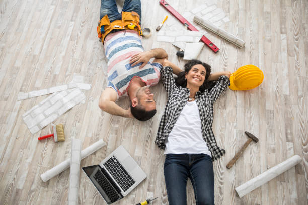 Couple renovating and resting on floor Couple renovating their home, resting and lying down on floor, high angle view. rebuilding stock pictures, royalty-free photos & images