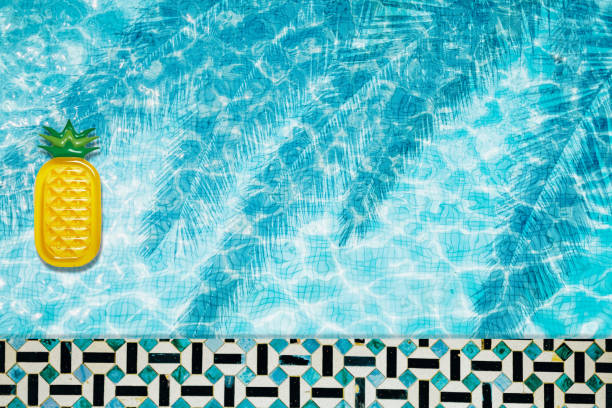 istock Pool floats, rings floating in a refreshing blue swimming pool with palm tree leaf shadows in water 975666774