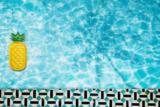 istock Pool floats, rings floating in a refreshing blue swimming pool with palm tree leaf shadows in water 975666842