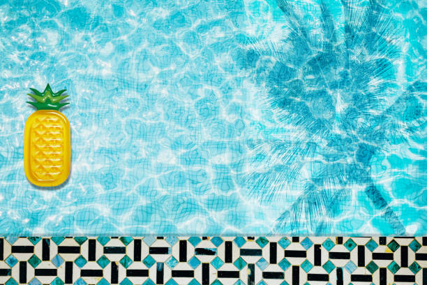 istock Pool floats, rings floating in a refreshing blue swimming pool with palm tree leaf shadows in water 975667248