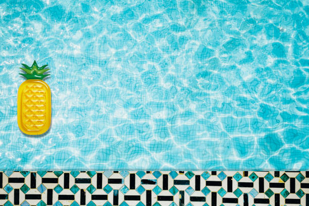 istock Pool floats, rings floating in a refreshing blue swimming pool with palm tree leaf shadows in water 975667256