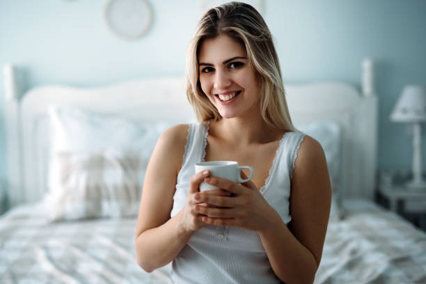 istock Young beautiful woman sitting on bed at home 975671268