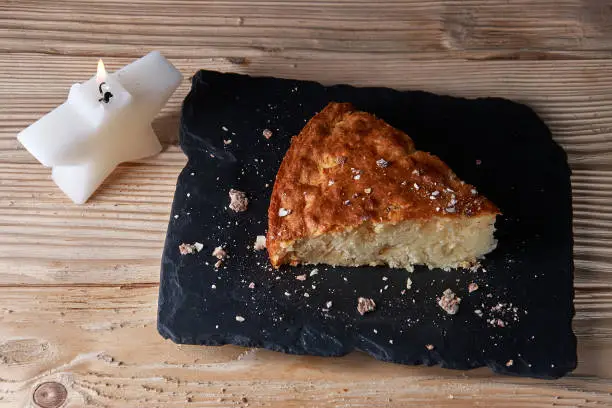 Photo of Home baked apple pie on shale board and wooden table near Candle in the form of stars
