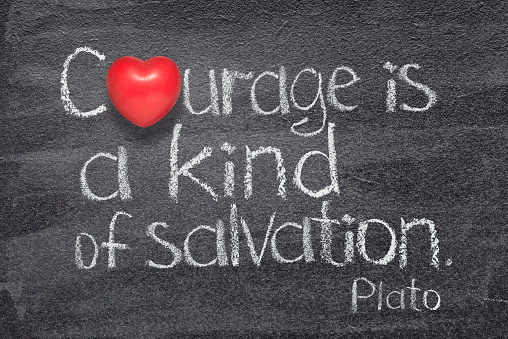 Courage is a kind of salvation quote of ancient Greek philosopher Plato written on chalkboard with red heart symbol instead of O