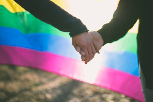 istock Happy lesbian couple holding hands over rainbow flag background 975676656