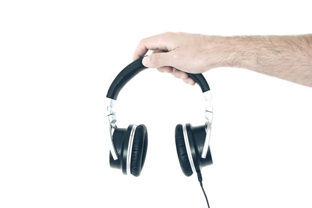 istock hand holding stereo headphones against white wall 975680914