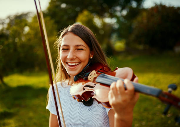 Cropped shot of a young girl playing a violin outdoors