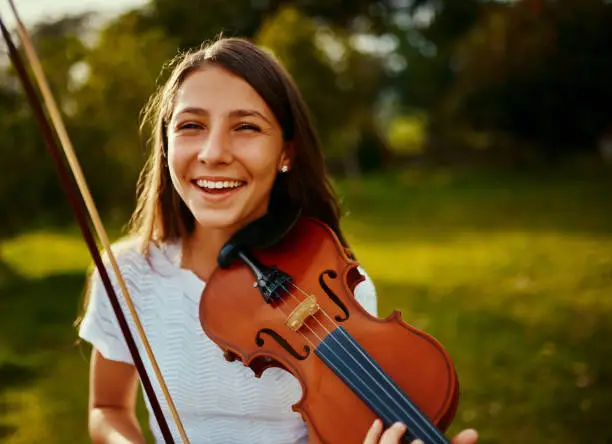 Cropped shot of a young girl playing a violin outdoors