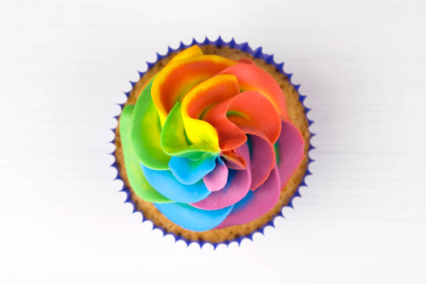 istock Cupcake with rainbow colorful cream in blue cup on white wooden table. 975688700