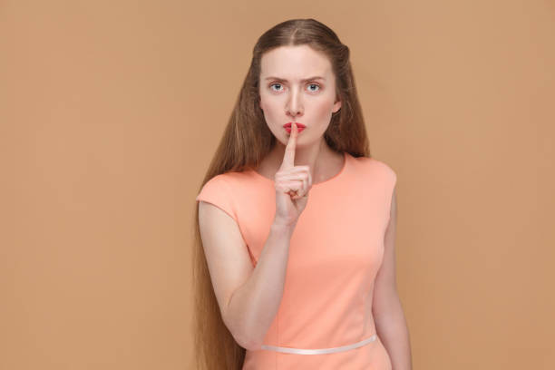 istock shhh sign, serious woman touching her lips with finger. 975689204