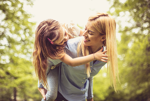 Smiling single mother playing in nature with daughter.