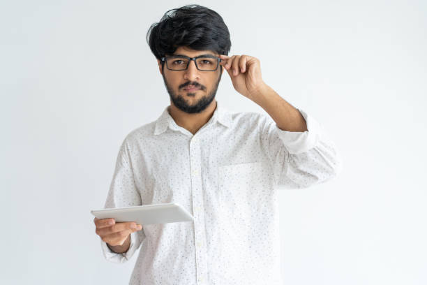 istock Serious concentrated male manager with tablet adjusting glasses 975698960