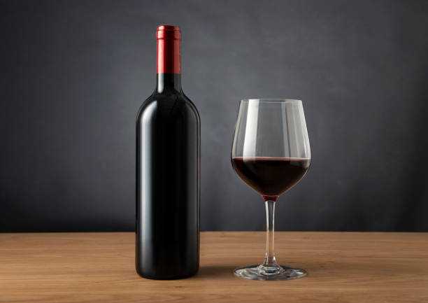 Cтоковое фото пустая бутылка вина и бокал красного вина на столе на темном черном фоне