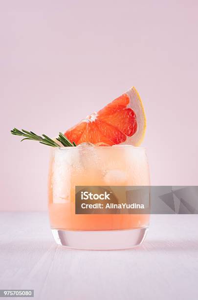 Cold Detox Cocktail Of Grapefruit Juice With Ice Rosemary Slices Citrus On Soft Light Pink And White Background Stock Photo - Download Image Now