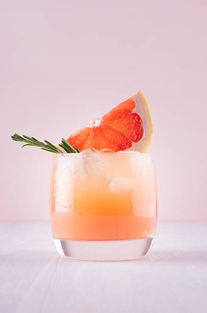 cold detox cocktail of grapefruit juice with ice, rosemary, slices citrus on soft light pink and white background. - grapefruit fruit freshness pink imagens e fotografias de stock