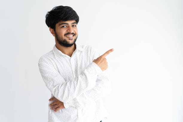 istock Smiling handsome young man pointing finger aside 975705400