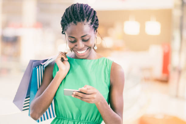 istock Smiling woman texting message in shopping mall 975713112