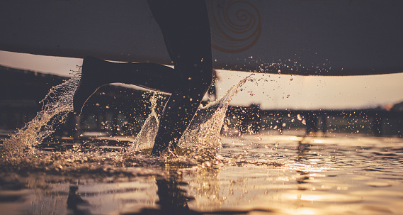 Low angle view on surfer running into the water with surfboard