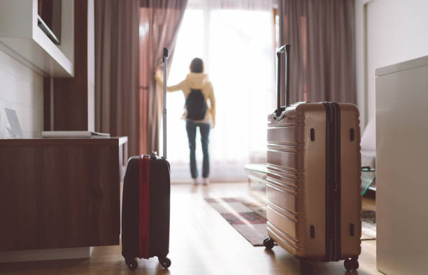 Tourist woman staying in luxury hotel Rear view of tourist in the hotel room pulling the curtains to see the view hotel window view stock pictures, royalty-free photos & images
