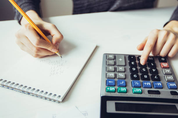 istock Closeup of Economist Using Calculator and Writing 975735822