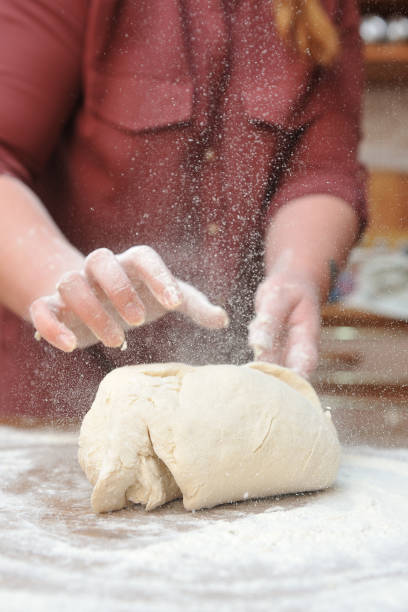 istock Women's hands knead the dough in the kitchen on the table 975742464
