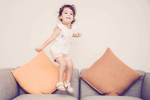 istock Carefree girl jumping on sofa 975743058