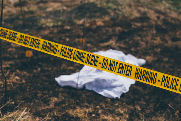 istock Dead body on the ground behind a cordon tape 975749024