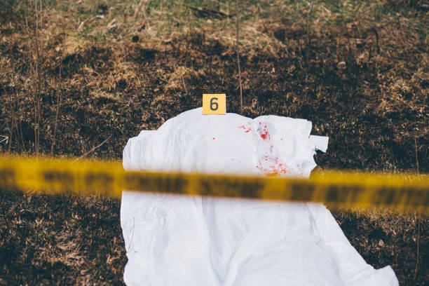 istock Dead body covered with white sheet with blood splash on it 975749136