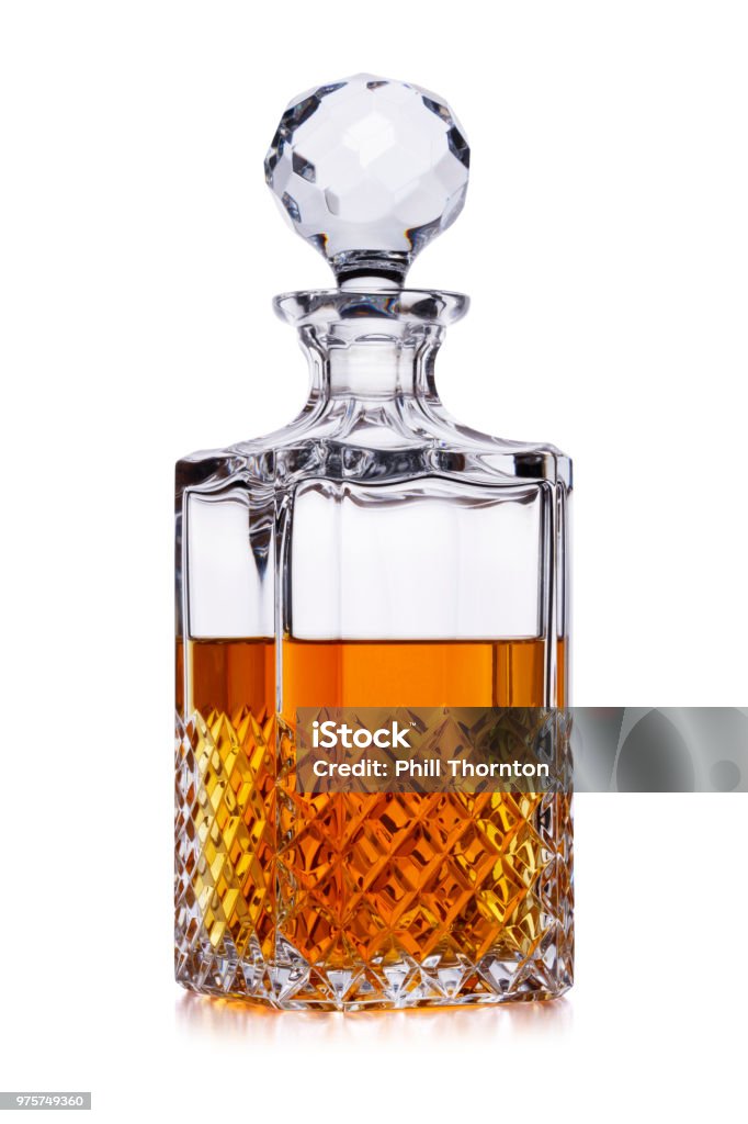 A half full crystal whisky decanter, with amber alcohol, shot on white, with a small reflection Decanter Stock Photo