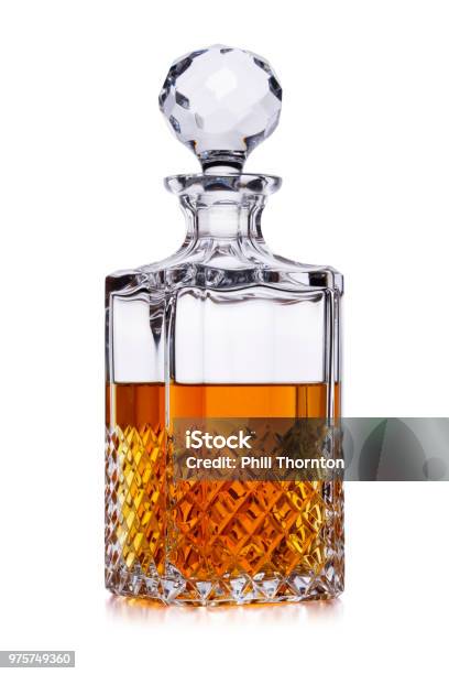 A Half Full Crystal Whisky Decanter With Amber Alcohol Shot On White With A Small Reflection Stock Photo - Download Image Now