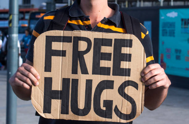 Man holding a cardboard sign with free hugs written on it stock photo