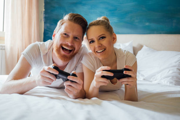 istock Happy couple lying down and playing video games at home 975777384