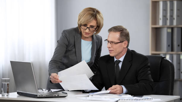 istock Boss looking through draft financial report done by his female accountant 975777842
