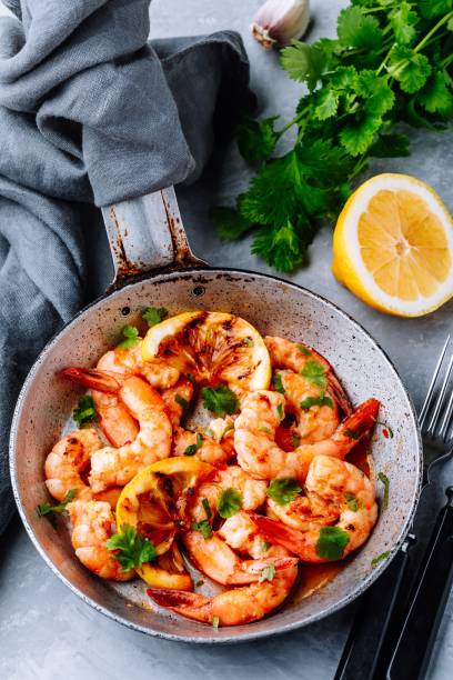 Spicy garlic chilli Shrimps on frying pan with lemon and cilantro Spicy garlic chilli Prawns Shrimps on frying pan with lemon and cilantro food state preparation shrimp prepared shrimp stock pictures, royalty-free photos & images