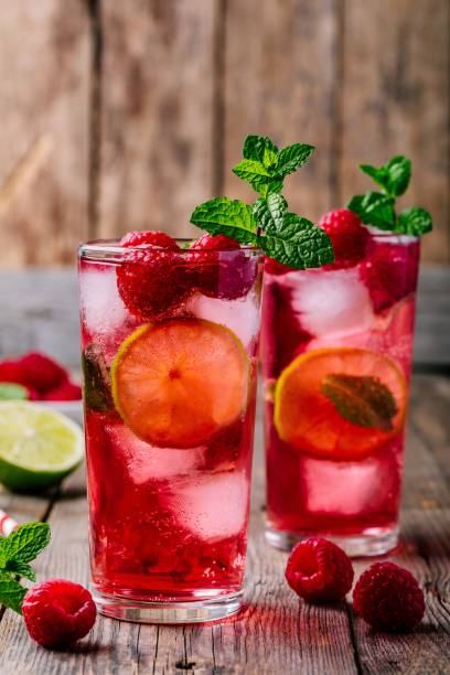 istock Raspberry Mojito Lemonade with lime and fresh mint in glass on wooden background 975787060