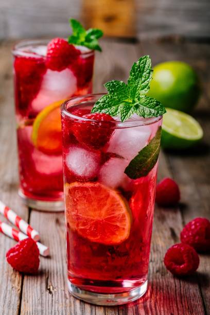 istock Raspberry Mojito Lemonade with lime and fresh mint in glass on wooden background 975789524